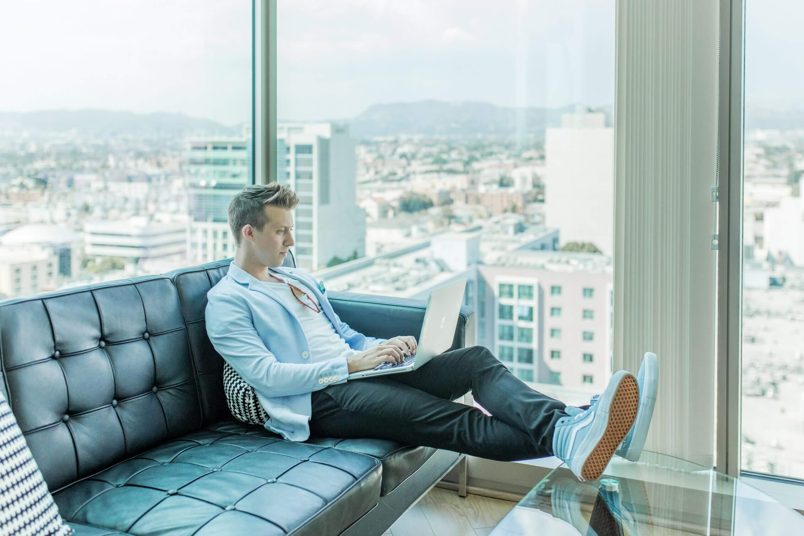 man sitting on sofa writing on a laptop