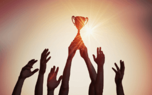 photo of a team holding up one trophy with arms outstretched