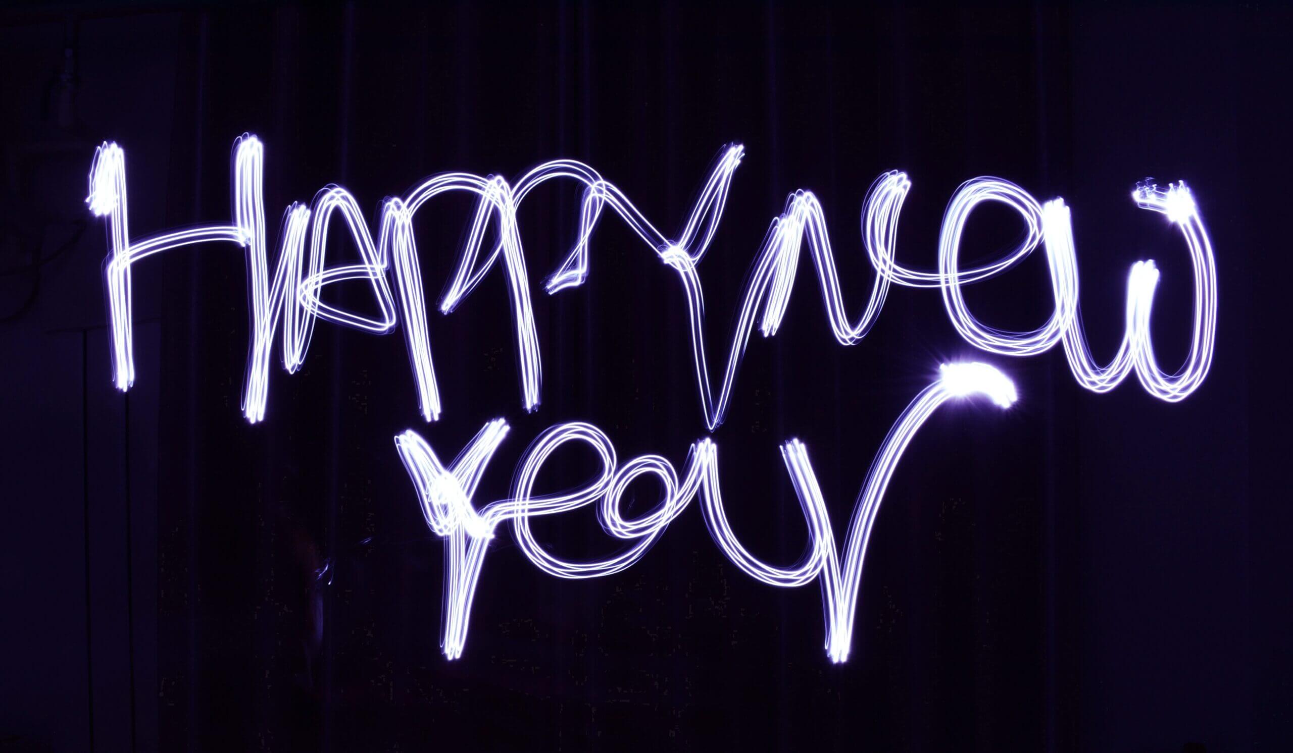 Light art spelling out "Happy New Year" in white on a dark background