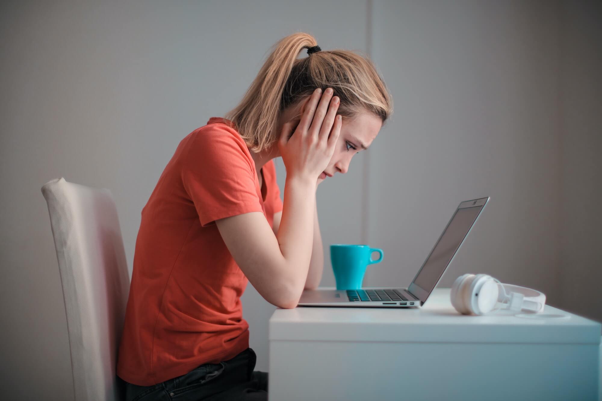 Woman at a desk, looking worried as she leans over her laptop