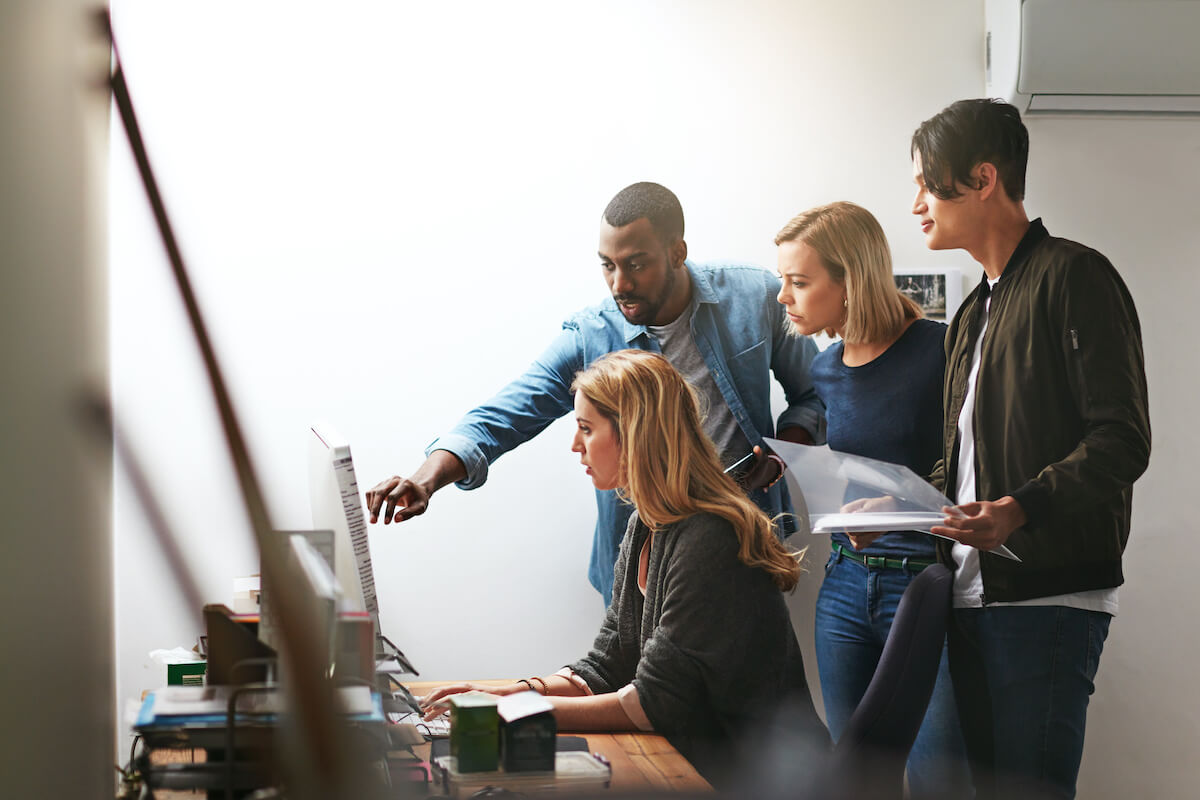 A group of people looking at a desktop computer screen.