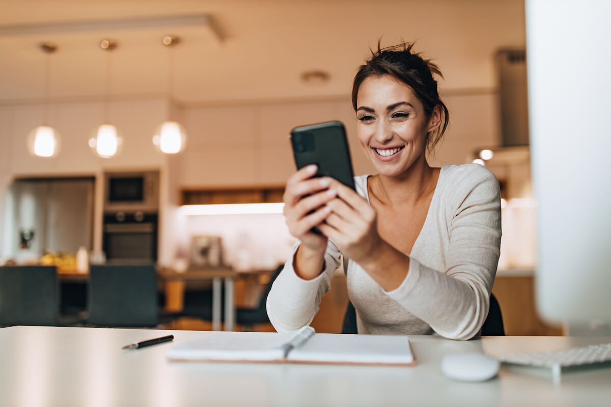 A woman holding her phone and watching a video on the future of SEO while smiling.