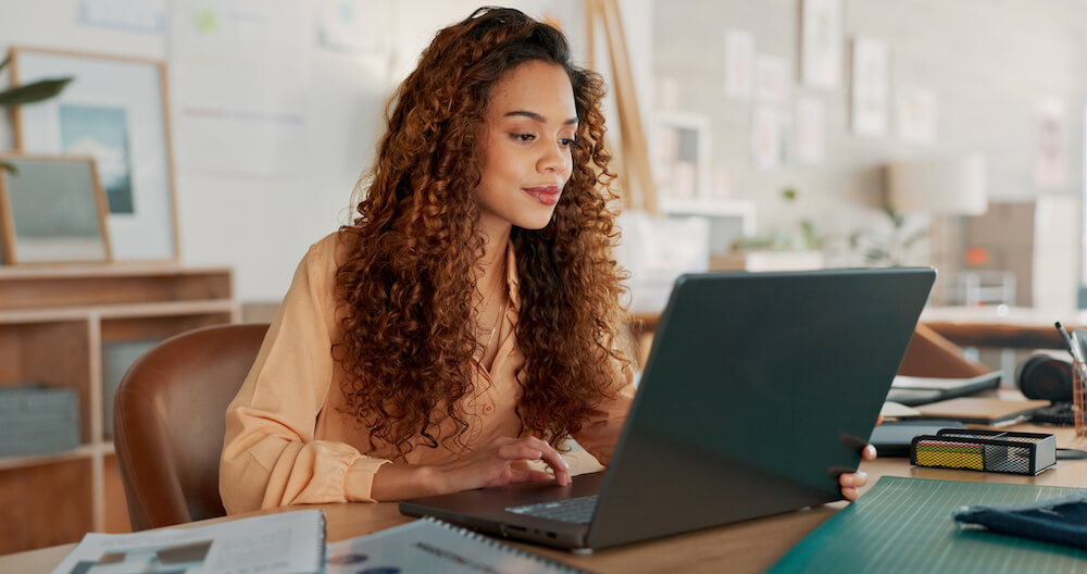 A woman looking at a laptop while looking at her content marketing and SEO strategy data.